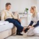 A health visitor putting on slippers on a senior woman at home at Christmas time.